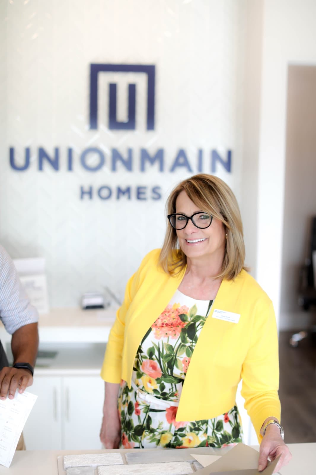 UnionMain Homes team member standing in front of the UnionMain Homes logo